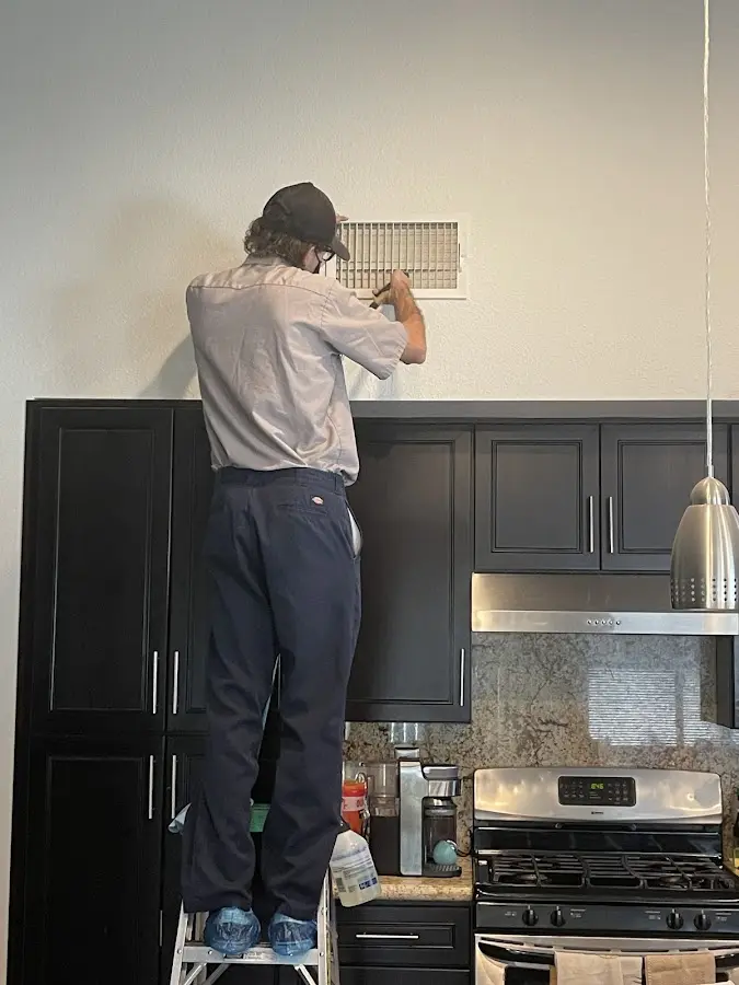 Technician inspecting an air vent during HVAC service in West Frankfort